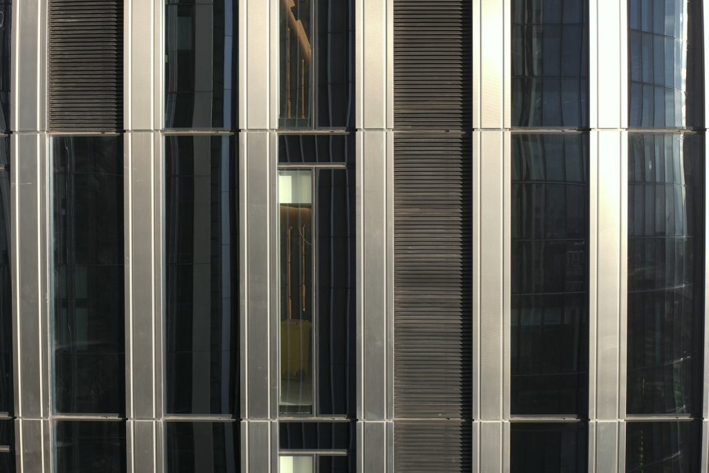 Close-range drone image of a metal-clad glazed façade with louvres, captured for façade inspection